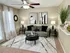 Elegant living room showcasing a modern gray sofa, chic black tables, abstract art, and lush greenery, bathed in natural light from floor-to-ceiling windows.