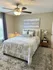 Charming bedroom with cozy ambiance, featuring elegant beddings, a stylish ceiling fan, and soft lighting for a relaxing retreat.