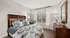 Charming bedroom with elegant wooden furniture, plush bedding with nature-themed prints, large window with sheer curtains, and stylish decor.