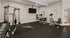 Modern fitness room equipped with versatile gym equipment, weights, and a flat-screen TV for an enhanced workout experience.