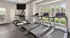 Modern fitness center with state-of-the-art treadmills and ellipticals, featuring large windows for natural lighting and garden views.