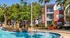 Inviting apartment complex featuring a sparkling pool surrounded by palm trees and cozy outdoor seating, perfect for relaxation.