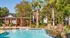 Inviting outdoor pool area with lush greenery, elegant pergola seating, and serene water features, offering a perfect retreat for relaxation.
