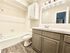 Elegant bathroom with modern fixtures, featuring a large mirror, sleek vanity, and pristine bathtub, complemented by stylish wood flooring.