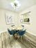 Chic dining area with stylish blue chairs and modern artwork, showcasing open access to a sleek kitchen.