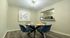 Contemporary dining area with sleek navy chairs around a round table, accented by modern artwork and stylish lighting.
