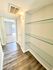 Inviting hallway with stylish glass shelves and modern lighting leading to a sunlit room with elegant flooring.