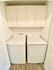Bright, efficient laundry space featuring modern washer and dryer with ample overhead storage cabinets.