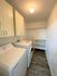 Bright and functional laundry room with modern washer and dryer, ample storage cabinets, and sleek shelving.