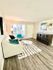 Bright and inviting living room with modern decor, featuring a cozy sofa, stylish armchair, and patterned rug on elegant wood flooring.