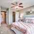 Bright and inviting bedroom featuring elegant decor, a plush pink bedspread, and a ceiling fan for comfort.