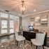 Elegant office space with chic white chairs, modern desk, artistic wall decor, and large windows for natural light.