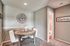 Cozy dining nook with elegant round table, stylish wall clock, and inviting decor, leading into a bright bathroom.