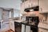 Charming kitchen with modern black stove, bright cabinetry, and cozy decor, including 'Happiness is Homemade' sign.