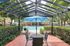 Charming patio view featuring a shaded pergola, stylish outdoor furniture, and a glistening pool surrounded by lush greenery.