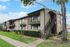 Charming two-story apartment building with balconies, nestled in a lush green setting, perfect for modern living.