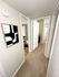 Inviting apartment hallway with plush carpeting, modern artwork, and access to bright, stylish bathrooms.
