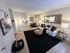 Chic and inviting living room with modern decor, featuring a cozy sofa, stylish coffee tables, and an elegant dining area in the background.