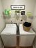 Charming laundry room with modern washer and dryer, bright decor, and ample storage space.