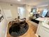 Chic apartment featuring a cozy dining area with a round table for four, modern open-plan living room with stylish decor, and inviting natural light.