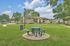 Charming outdoor space in a tranquil apartment community featuring lush green lawns, cozy picnic tables, and inviting paths under a sunny sky.