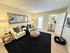 Inviting living room featuring cozy beige sofa, stylish round wooden tables, and integrated laundry space for modern convenience.