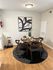 Inviting dining area with a modern wooden table set for four on a stylish black and white rug, complemented by contemporary wall art. Perfect blend of comfort and elegance.