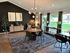 Elegant living space with modern decor, featuring a chic chandelier, large windows offering natural light, and a stylish dining area on wooden flooring.