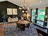 Charming living space with elegant decor, featuring a stylish wooden table, modern light fixture, and large windows with a lush garden view.