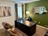 Sophisticated home office with stylish dark desk, leather chairs, and elegant decor, featuring a large art piece and modern lighting.
