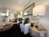 Inviting living space with modern decor featuring a cozy white sofa, stylish glass lamp, and rustic wooden tables in a beautifully lit apartment.