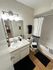 Inviting bathroom with elegant lighting, sleek white vanity, and stylish black and white accents.