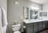 Elegant bathroom featuring double vanity with sleek dark cabinets, modern fixtures, and bright lighting, complemented by a fresh towel display and decorative orchids for a luxurious touch.