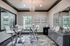 Elegant dining area with modern glass table and stylish chairs, accented by a chic chandelier and large windows offering abundant natural light.