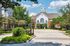 Charming apartment complex entrance surrounded by lush greenery and a well-maintained garden, featuring elegant architecture and a welcoming ambiance.