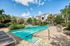 Inviting apartment complex featuring a sparkling swimming pool surrounded by lush landscaping and modern architecture on a bright sunny day.