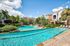 Luxurious apartment complex with a stunning outdoor pool, surrounded by lush greenery and elegant architecture.
