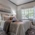 Elegant bedroom with cozy bedding and chic decor, featuring a large window offering abundant natural light.