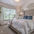 Inviting bedroom with plush bedding, elegant decor, and large window offering serene natural light.