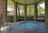 Charming outdoor area with a round bubbling spa, gracefully surrounded by stone pillars and lush greenery, offering a serene retreat.