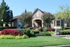 Charming brick home with lush landscaping, vibrant flowers, and a welcoming front entrance.
