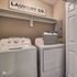 Charming laundry room with modern washer and dryer, featuring an elegant Laundry Co. sign and organized shelving.