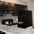 Elegant kitchen with dark wood cabinets, sleek black appliances, and marble-patterned countertops.