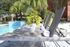 Luxurious poolside relaxation area with modern sun loungers, lush greenery, and a sparkling blue swimming pool.