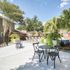 Inviting outdoor patio with chic seating, lush greenery, and sunlit lounge chairs, perfect for relaxing and socializing.