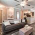 Elegant living room with modern gray sofa, chic ceiling fan, and open kitchen layout, accented with stylish decor and soft lighting.