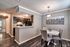 Chic dining area with elegant lighting and modern kitchen featuring sleek appliances and stylish dark cabinetry.