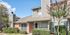 Charming suburban apartment with modern siding, lush landscaping, and vibrant blooming trees under a clear blue sky.
