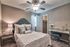 Chic and cozy bedroom featuring a plush bed with elegant pillows, mirrored vanity with seating, and a spacious walk-in closet in a modern neutral palette.