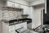 Modern kitchen featuring sleek black countertops, contemporary backsplash, and stainless steel appliances.